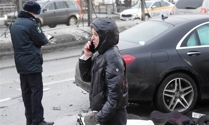 Девушка звонит по телефону возле автомобилей, пострадавших в результате ДТП